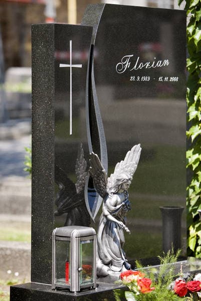 Schwarzer Granit-Grabstein mit kursiver Inschrift „Florian", eingraviertem Kreuz und kniendem Engel