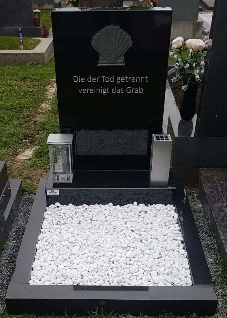 Schwarzer Granit-Grabstein mit eingravierter Muschel und Inschrift „Die der Tod getrennt vereinigt das Grab"
